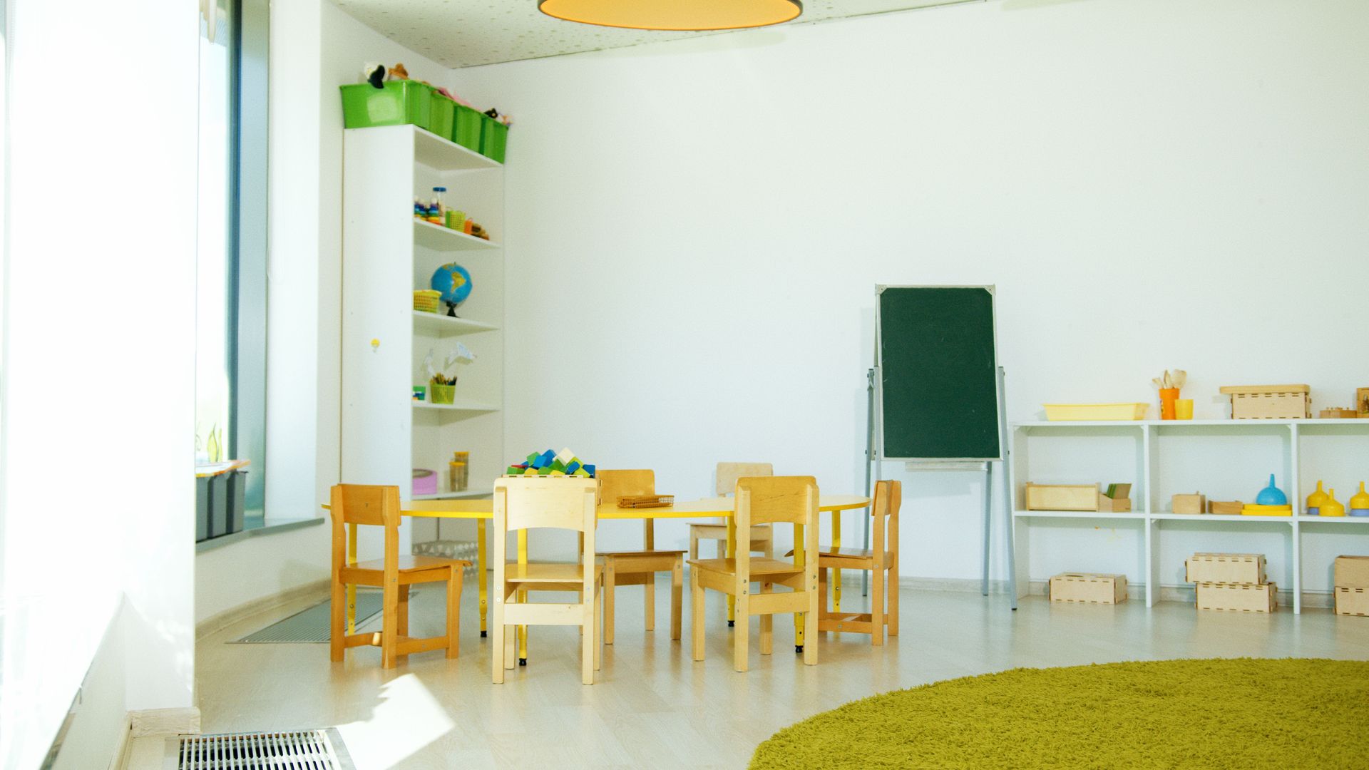 A well-lit, colorful kindergarten classroom with chairs, tables, and educational materials.